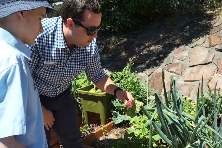 A students and teacher working in a garden.