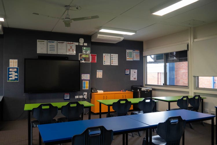 A classroom with desks and a large main learning display.