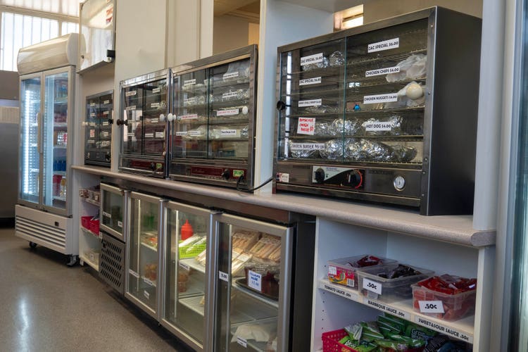 Inside the canteen with fridges and food warmers.